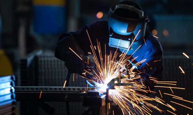 Workers wearing industrial uniforms and Welded Iron Mask at Steel welding plants, industrial safety first concept.