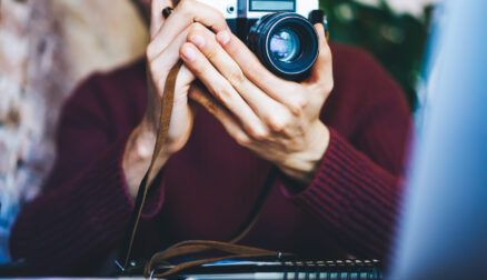 Selective focus on man's hands holding vintage camera with modern lense.